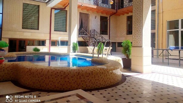 A pool area with a tiled floor, a pool, and a staircase leading to an upper level. - hotel Shams Bukhara (Bukhara)