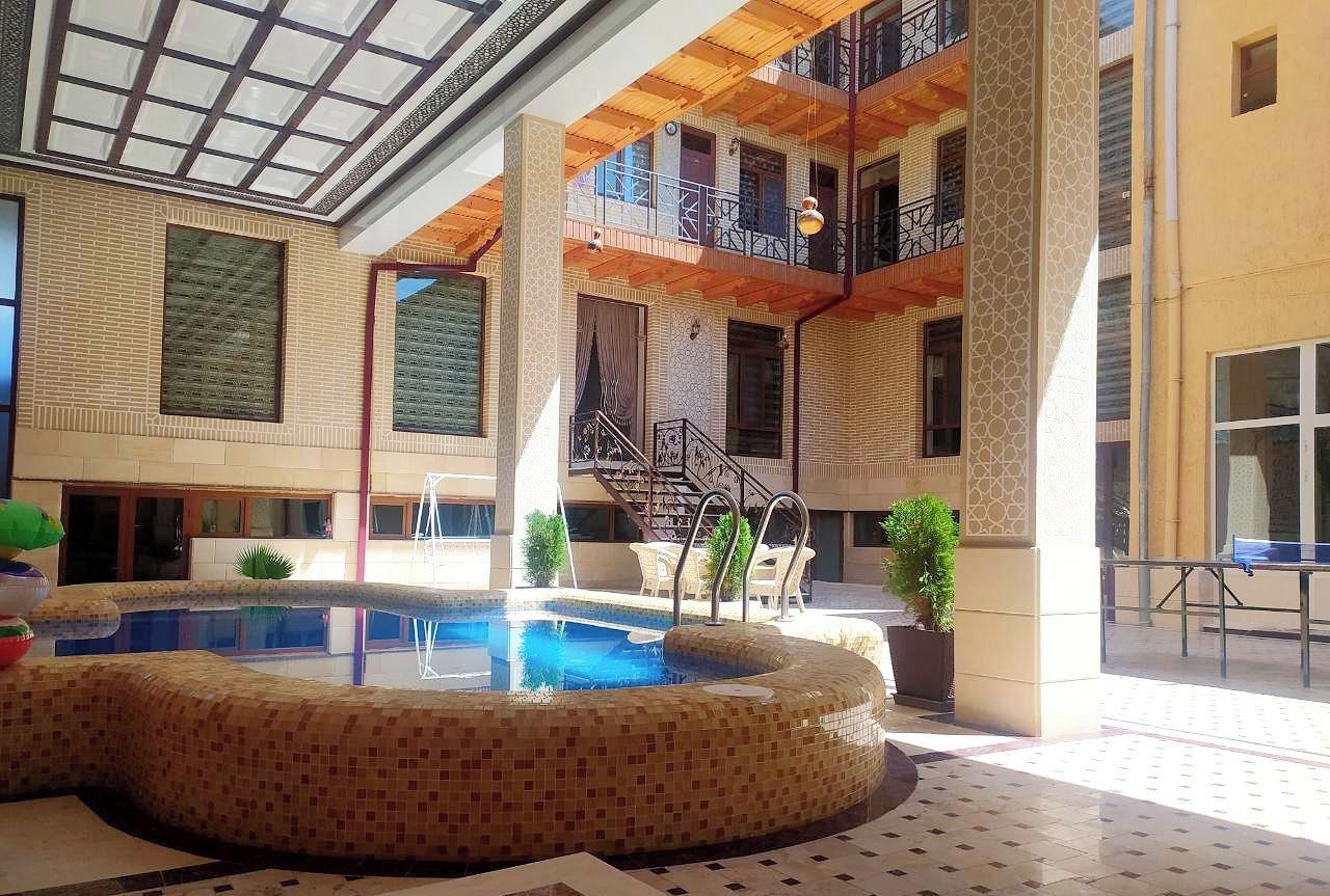 Zona de piscina con suelo de baldosas, una piscina y una escalera que conduce a un nivel superior.