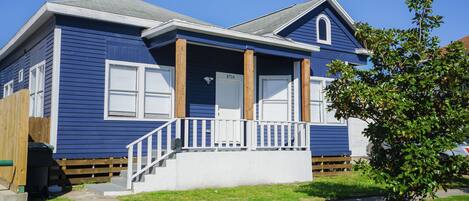 A two-story house with a front porch, wooden steps, and a mailbox.