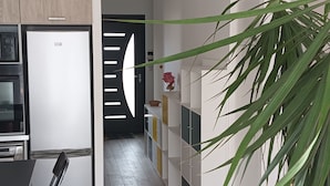 A modern kitchen with a dining area, wooden flooring, and a large green plant. - Appartement se Trouvant au Premier Étage D'une Maison Individuelle (Marseille)