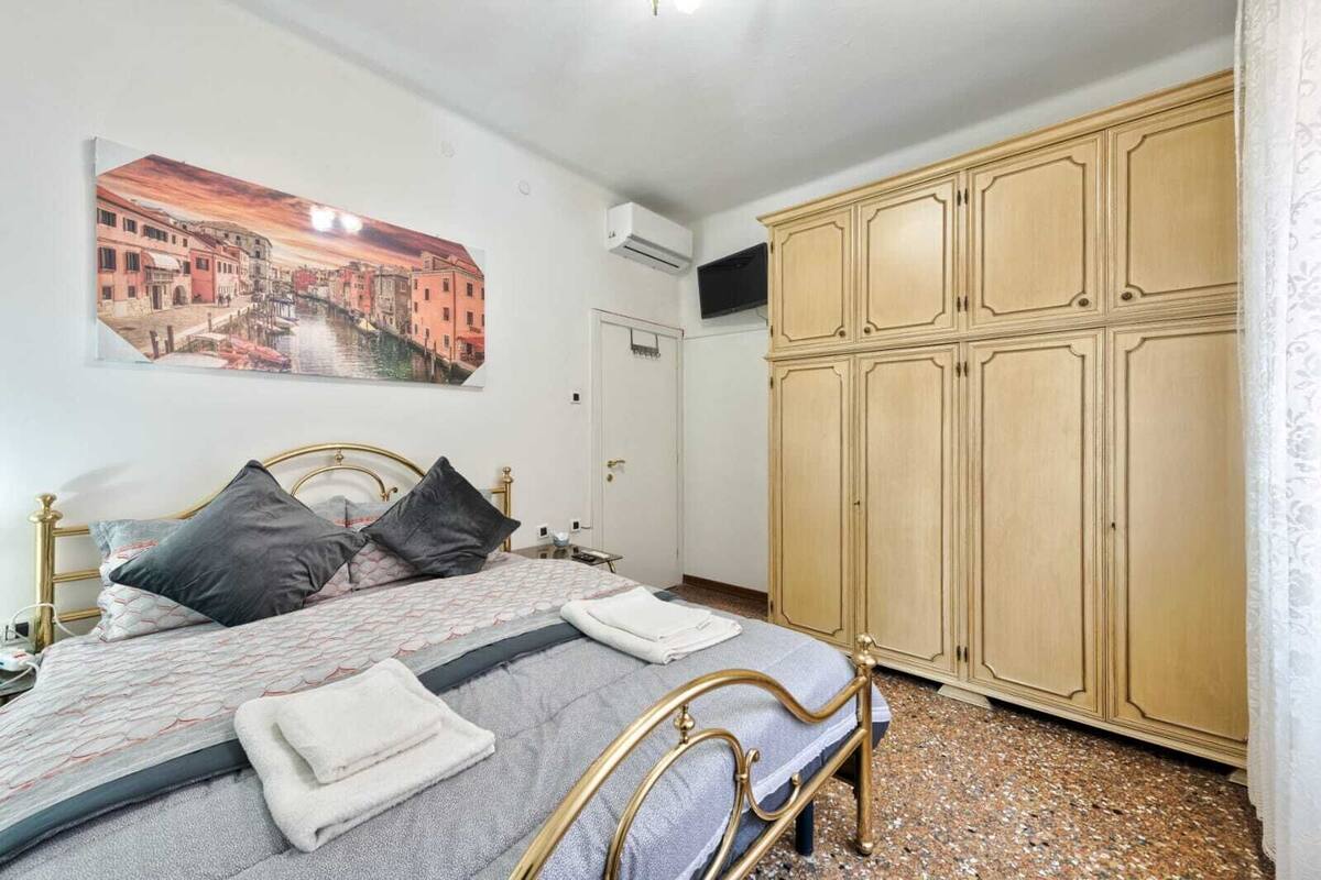 Un dormitorio con cama, armario, un cuadro y equipo de aire acondicionado.