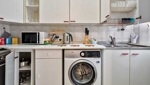Cocina compacta con microondas, cafetera, hervidor y lavadora.