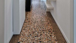 Un pasillo con paredes blancas, piso moteado y una lámpara en el techo.