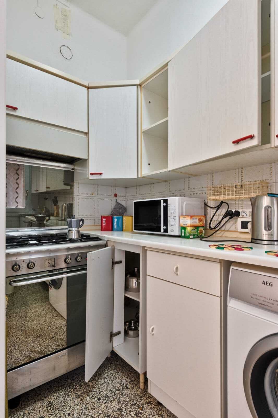 A compact kitchen with a stove, microwave, and washing machine.