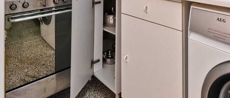 A compact kitchen with a stove, microwave, and washing machine.