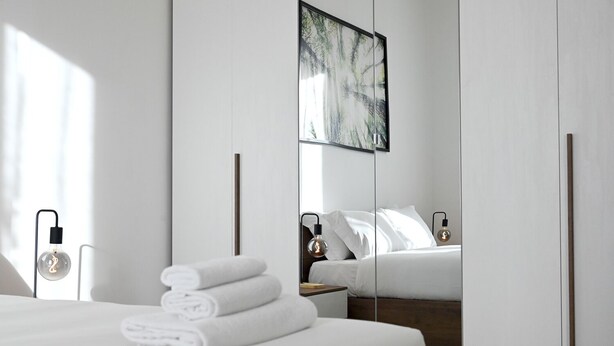 A modern hotel room with a neatly made bed, a large mirror, and a painting on the wall. - St Peter DOC house (Roma)
