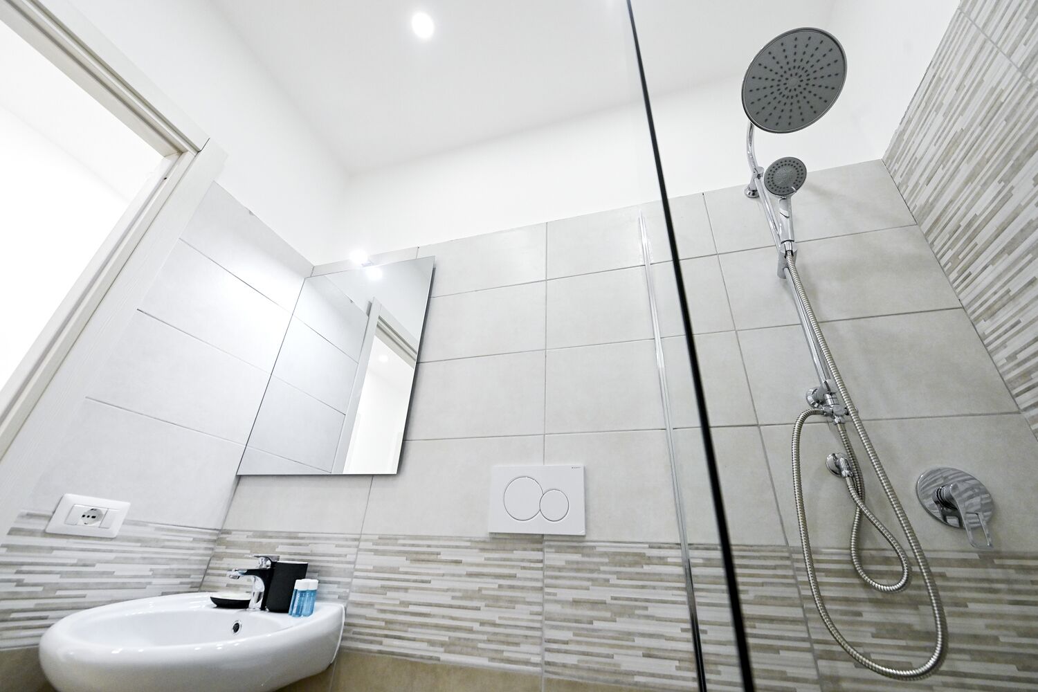 Un baño moderno con ducha, lavamanos y espejo.