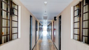 A long, narrow hallway with doors on both sides, a tiled floor, and a ceiling with lights and a smoke detector. - OYO Life 93086 Apartemen The Suite Metro By Abbah Property (Bandung)