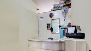 A reception desk with a glass top, a Canon printer, and a wall-mounted clock. - OYO Life 93086 Apartemen The Suite Metro By Abbah Property (Bandung)