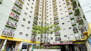 A high-rise building with multiple balconies and a central courtyard with a tree. - OYO Life 93086 Apartemen The Suite Metro By Abbah Property (Bandung)