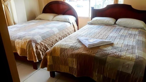 Dos camas individuales con cabeceros de madera, una colcha acolchada y una toalla doblada en la cama de la derecha.