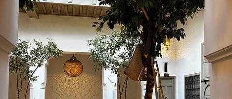 An indoor courtyard with a seating area, a large tree, and decorative lanterns.
