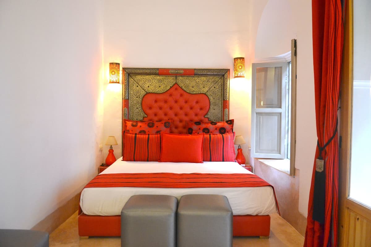 A bedroom with a large bed, two bedside tables, and a window with curtains.