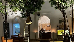 A cozy indoor setting with a dining area, a seating area, and a decorative tree. - Riad See Moon et Spa (Marrakech)
