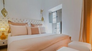 A bedroom with a tufted headboard, a large bed with multiple pillows, a nightstand with a lamp, and a wardrobe with a window. - Riad See Moon et Spa (Marrakech)