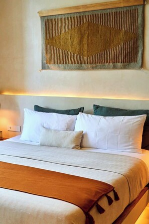 Ein ordentlich bezogenes Bett mit weiĂen Leinen und mehreren Kissen, ein hölzerner Kopfteil und ein Wandteppich.
