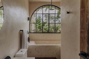A narrow staircase with a curved wall and a window with a metal grid.