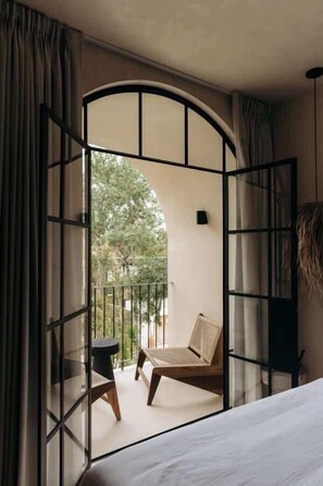 A room with a bed, a small table, and a chair. There is a balcony with a view of trees. - Casa Zebrina Romantic Design Apartment Beach Club (Tulum)