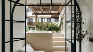 Een modern interieur met een minimalistisch design, met een witte bank, een trap en uitzicht op buiten.