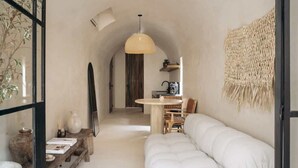 Een gezellig interieur met een witte bank, een houten tafel en een hanglamp.