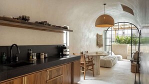 Een moderne keuken met houten kastjes, een zwart aanrechtblad en een eethoek met een ronde tafel en stoelen.