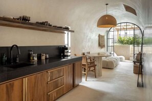 Une cuisine moderne avec des meubles en bois, un plan de travail noir et un coin repas comprenant une table ronde et des chaises.