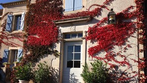 A building with a stone facade, red ivy, and a white door. - Grande Maison Avec vue Exceptionnelle sur le Lot (Calvignac)