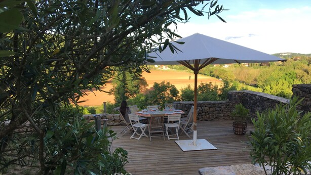 A wooden deck with outdoor furniture, a stone wall, and a view of a golf course. - Grande Maison Avec vue Exceptionnelle sur le Lot (Calvignac)