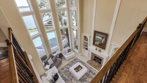 Un salón amplio con una ventana grande que da a una piscina, una chimenea y una escalera.