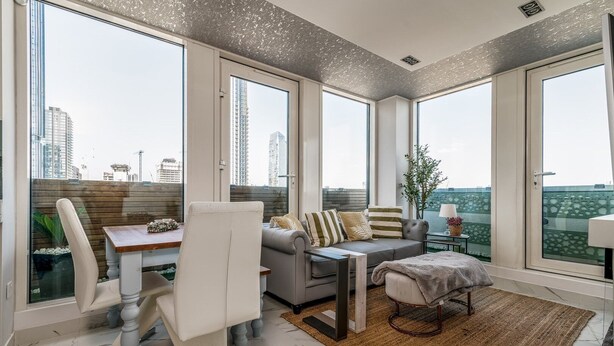 Ein modernes Wohnzimmer mit Essbereich, großen Fenstern und Blick auf die Stadtlandschaft.