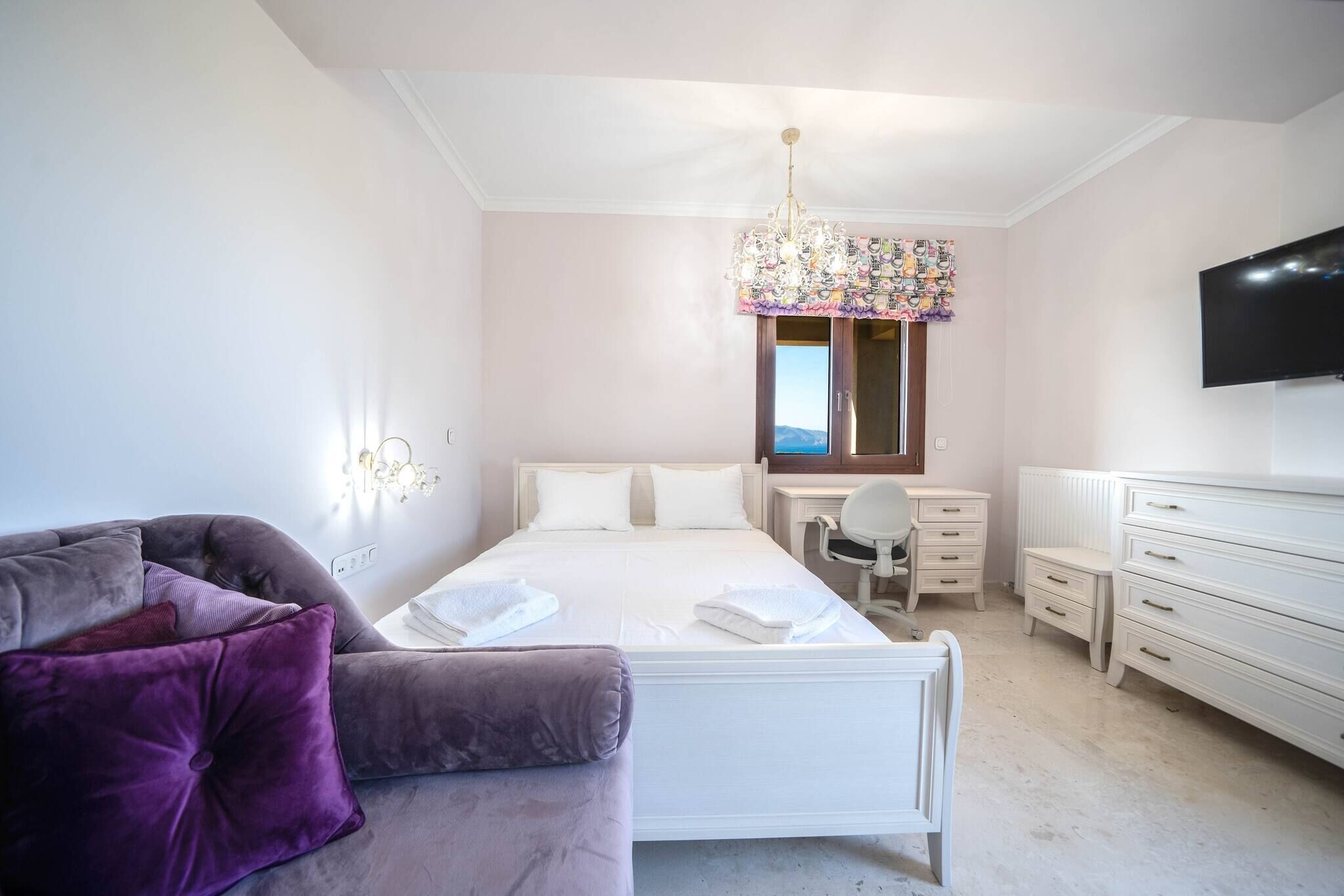 Een slaapkamer met een bed, een bureau, een stoel, een televisie en een bank.