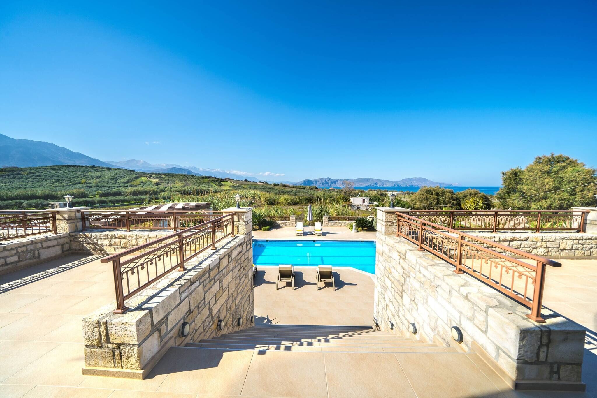 A pool with a view of mountains, stone walls, and a clear sky.