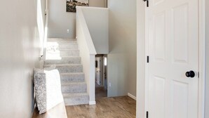 A hallway with a wooden bench, a white door, and a staircase leading to another room. - Easy Access I29 & I94 - Family Friendly - Spacious (Fargo)