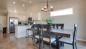 A modern kitchen with white cabinets, a stainless steel refrigerator, and a dining area with a wooden table and chairs. - Easy Access I29 & I94 - Family Friendly - Spacious (Fargo)