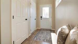 A hallway with two white doors, a small window, and a patterned rug. - Easy Access I29 & I94 - Family Friendly - Spacious (Fargo)