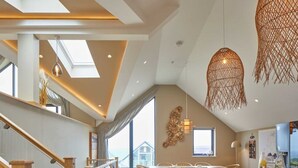Una cocina moderna con una encimera larga, taburetes de madera y vistas al exterior.
