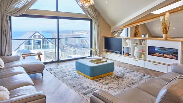 Un salón espacioso con un gran ventanal, un televisor de pantalla plana y una zona de estar acogedora.