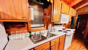 A wooden cabin kitchen with a white stove, sink, and cabinets. - Spectacular Views to Remember! Near hiking, biking, wineries, pet friendly (Fleetwood)