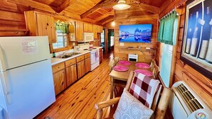 A wooden cabin interior with a kitchen, dining area, and a TV mounted on the wall. - Spectacular Views to Remember! Near hiking, biking, wineries, pet friendly (Fleetwood)