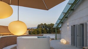 Une terrasse extérieure moderne dotée d’un jacuzzi, d’un espace salon et de grandes suspensions lumineuses.