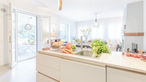 A modern kitchen with a large island, a sink, and a dining area visible through glass doors.
