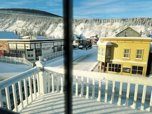 Eine verschneite Stadt mit Gebäuden, darunter ein Red Feather Saloon und ein Holzhaus mit schneebedecktem Dach.