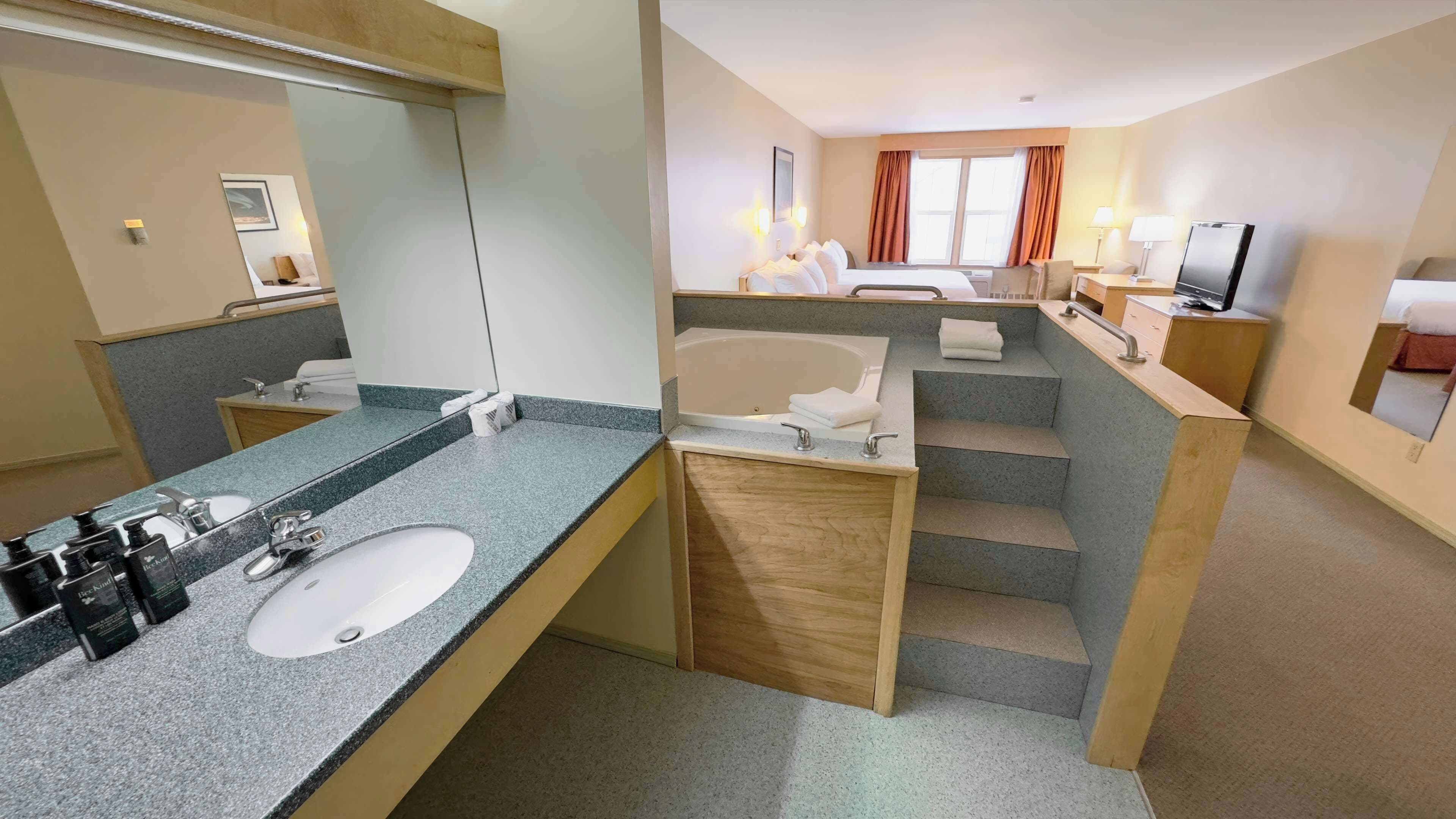 A hotel bathroom with a sink, mirror, and bathtub.