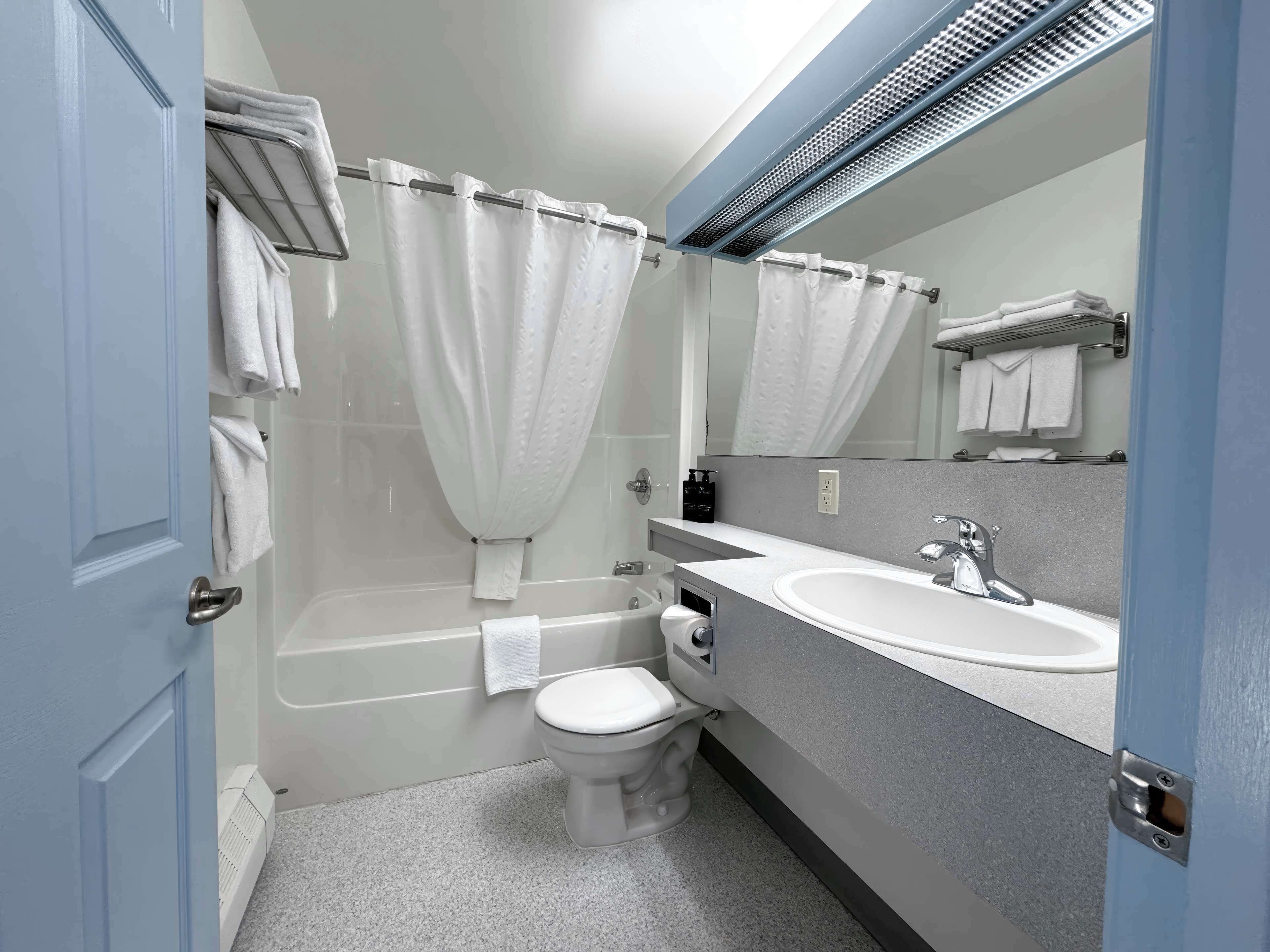A bathroom with a bathtub, toilet, and sink, with towels hanging on the wall.