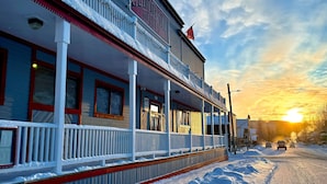 A hotel with a covered porch, a sign reading 'Floyd Hotel,' and a sunset in the background. - Eldorado, a Coast Hotel (Dawson City)