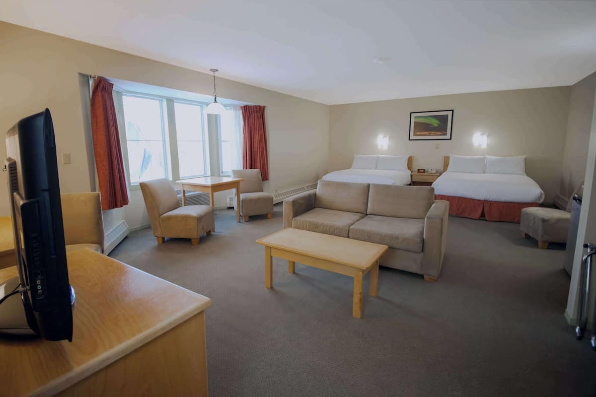 A hotel room with a bed, a sofa, a desk, a TV, and a window with curtains.