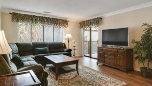 A living room with a sofa, coffee table, TV, and a potted plant. - Awesome Hilton Head Coligny Beach townhome! (Hilton Head Island)