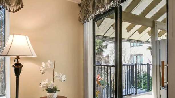 A room with a large sliding glass door leading to a balcony with a metal railing and greenery. - Awesome Hilton Head Coligny Beach townhome! (Hilton Head Island)