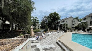 A poolside area with lounge chairs, a pool, and a wooden deck. - Awesome Hilton Head Coligny Beach townhome! (Hilton Head Island)