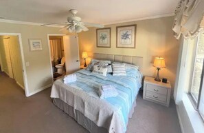 A bedroom with a bed, two bedside tables, a ceiling fan, and two wall-mounted lamps.